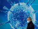 Un homme passe devant une illustration d'un virus à l'extérieur d'un centre scientifique régional à Oldham, en Grande-Bretagne, sur une photo d'archive du 3 août 2020. De nouvelles recherches explorent la possibilité que le 