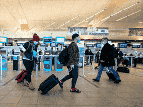 Les voyageurs transportent leurs bagages jusqu'à leurs vols à l'aéroport international d'Edmonton le 2 décembre 2021.