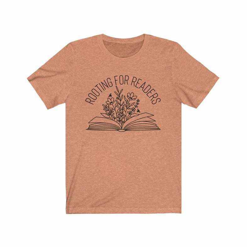 Image d'un t-shirt orange avec les mots "enracinement pour les lecteurs." Au-dessous du texte se trouve un livre avec des fleurs s'élevant du centre. 