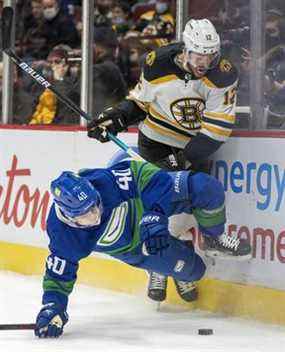 L'ailier droit des Bruins de Boston Craig Smith (12) se bat pour le contrôle de la rondelle avec le centre des Canucks de Vancouver Elias Pettersson (40) lors de la première période de la LNH à Vancouver, le mercredi 8 décembre 2021.