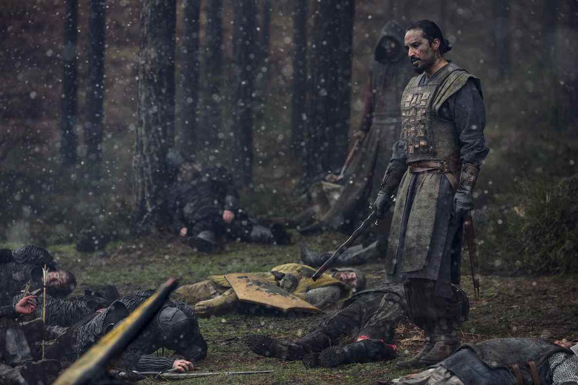 Un soldat se tient au-dessus d'un champ de bataille enneigé d'autres soldats morts dans The Witcher de Netflix