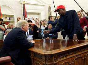 Le rappeur Kanye West montre son téléphone portable au président américain Donald Trump lors d'une réunion dans le bureau ovale de la Maison Blanche à Washington, DC, le 11 octobre 2018.