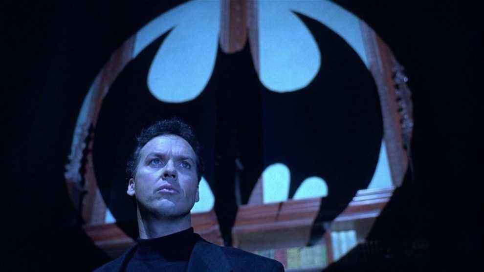 Bruce Wayne (Michael Keaton) debout devant une silhouette du signal de chauve-souris dans Batman Returns.
