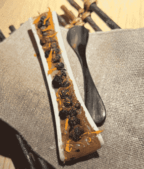 Dessert dans l'os de fémur d'un chevreuil, fourré de fondant fondu de moelle de cerf aux myrtilles et fleurs de colangela, de Noma.
