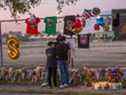 Dans cette photo d'archive prise le 7 novembre, Isaac Hernandez et Matthias Coronel regardent Jesus Martinez signer un panneau commémoratif dans un mémorial de fortune sur le terrain de NRG Park où huit personnes sont mortes dans une vague de foule au Astroworld Festival à Houston, Texas. 