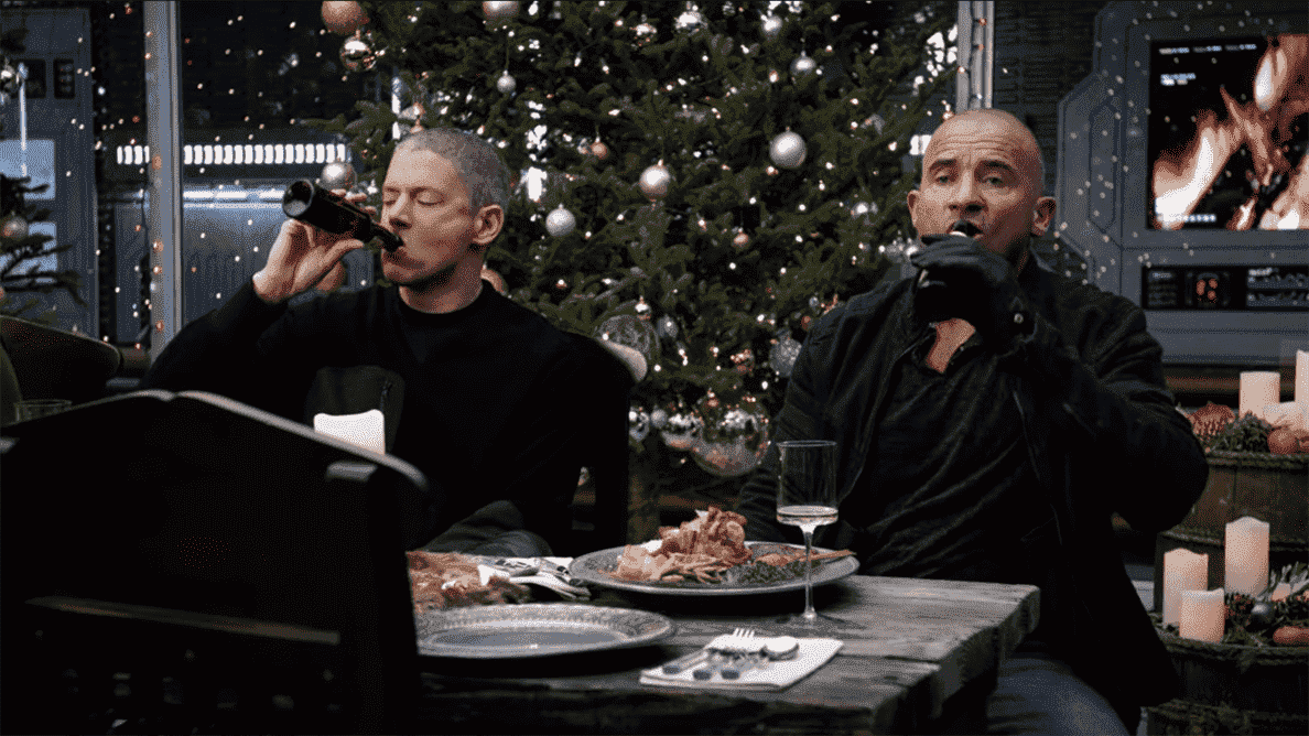 Captain Cold (Wentworth Miller) et Heat Wave (Dominic Purcell) renversent des bières à la table du dîner de Noël dans Legends of Tomorrow. 