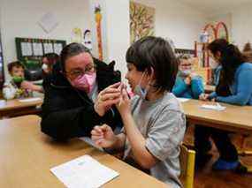 Un parent aide un enfant à effectuer un test rapide d'antigène dans une école primaire