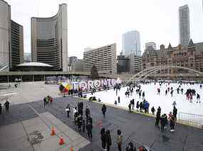 Des gens patinent au Nathan Phillips Square devant l'hôtel de ville de Toronto le 23 décembre 2021.