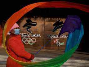 Une femme fait voler un ruban près des logos des Jeux olympiques et paralympiques de Pékin 2022 dans un parc de Pékin, en Chine, le 8 décembre 2021.