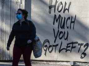 Un piéton portant un masque passe devant des graffitis déclarant 