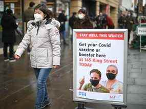Une femme passe devant une signalisation à l'extérieur d'un centre de vaccination contextuel pour le vaccin ou le rappel Covid-19, à Hammersmith et Fulham dans le Grand Londres le 3 décembre 2021, alors que le déploiement s'accélère en Angleterre.