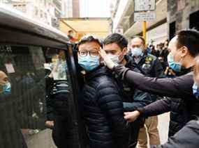 Le rédacteur en chef par intérim de Stand News Patrick Lam, l'une des six personnes arrêtées "pour complot en vue de publier une publication séditieuse" selon le département de la sécurité nationale de la police de Hong Kong, est escorté par la police alors qu'ils partent après que la police a fouillé son bureau à Hong Kong, Chine, le 29 décembre 2021.