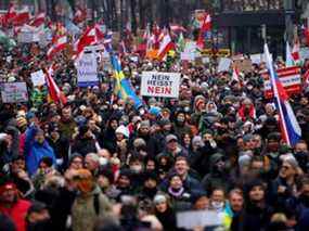 Des manifestants brandissent des drapeaux et des pancartes alors qu'ils marchent pour protester contre les restrictions COVID-19 et le mandat de vaccination à Vienne, en Autriche, le samedi 11 décembre 2021.