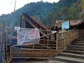 Un homme marche derrière une pancarte affichée sur le lieu du festival Hornbill qui a été fermé après que les forces de sécurité indiennes ont tué 13 civils dans l'État du nord-est du Nagaland en tirant sur un camion et plus tard en tirant sur une foule qui s'était rassemblée pour protester contre l'attaque, dans le village de Kisama à Kohima le 5 décembre 2021.