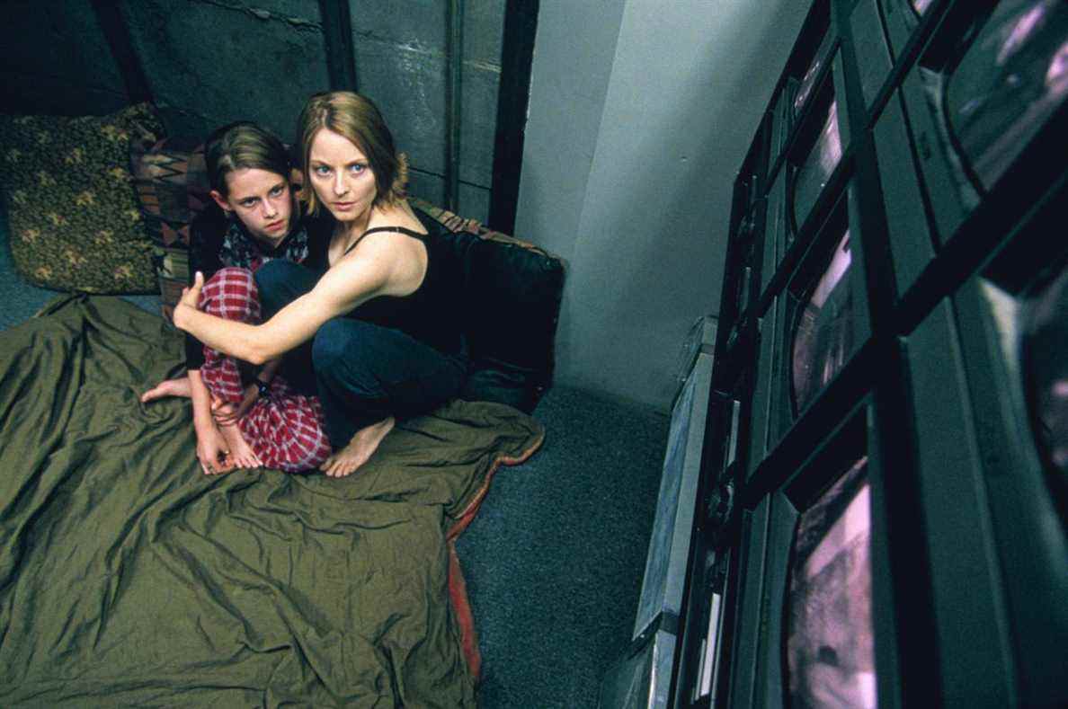Jodie Foster et Kristen Stewart se blottissent sur une couverture verte tout en regardant un mur d'écrans dans Panic Room.