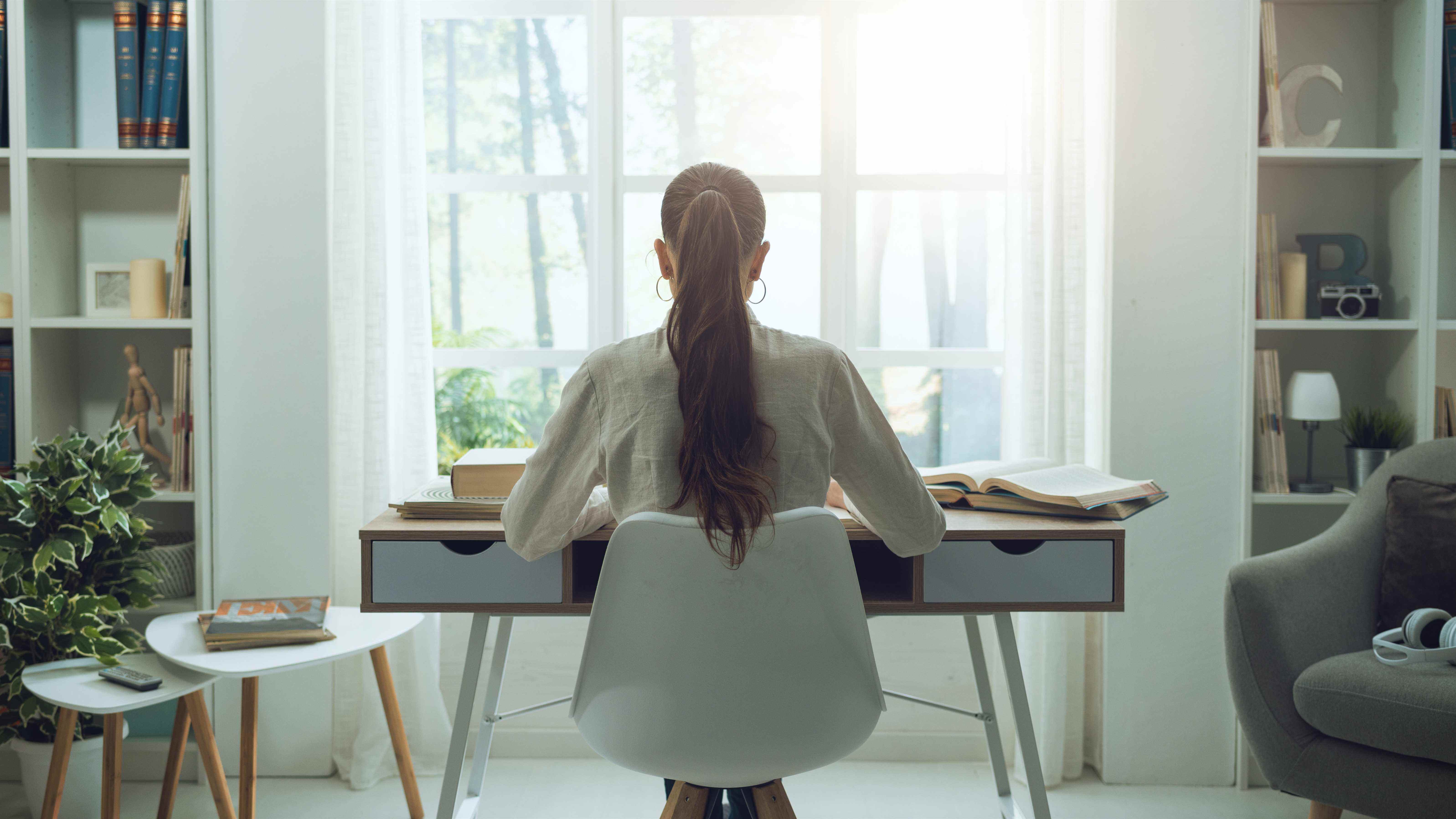 Une femme assise à un bureau devant une grande fenêtre