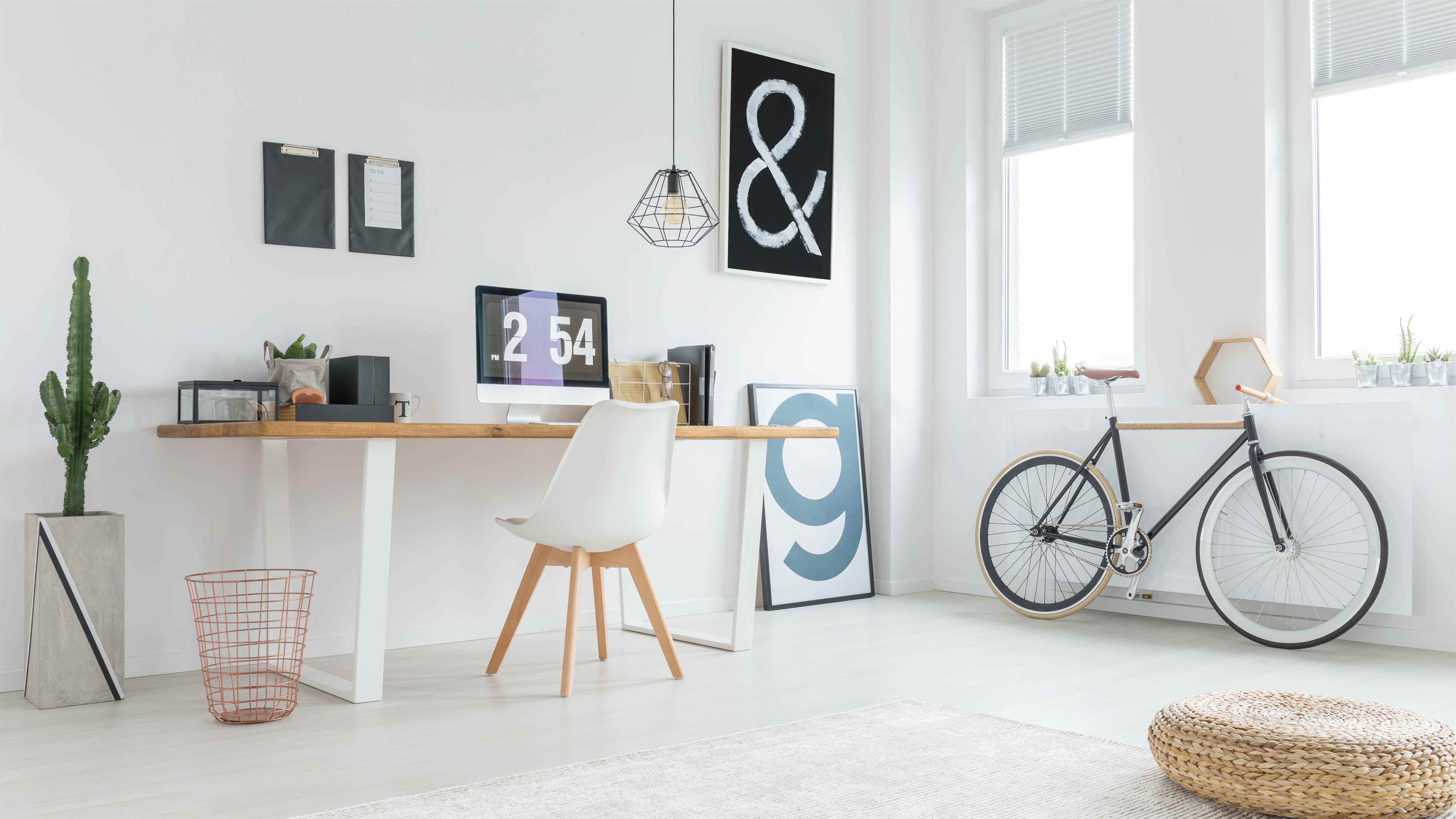 Un bureau à domicile peint en blanc avec un cactus et un vélo à côté du bureau