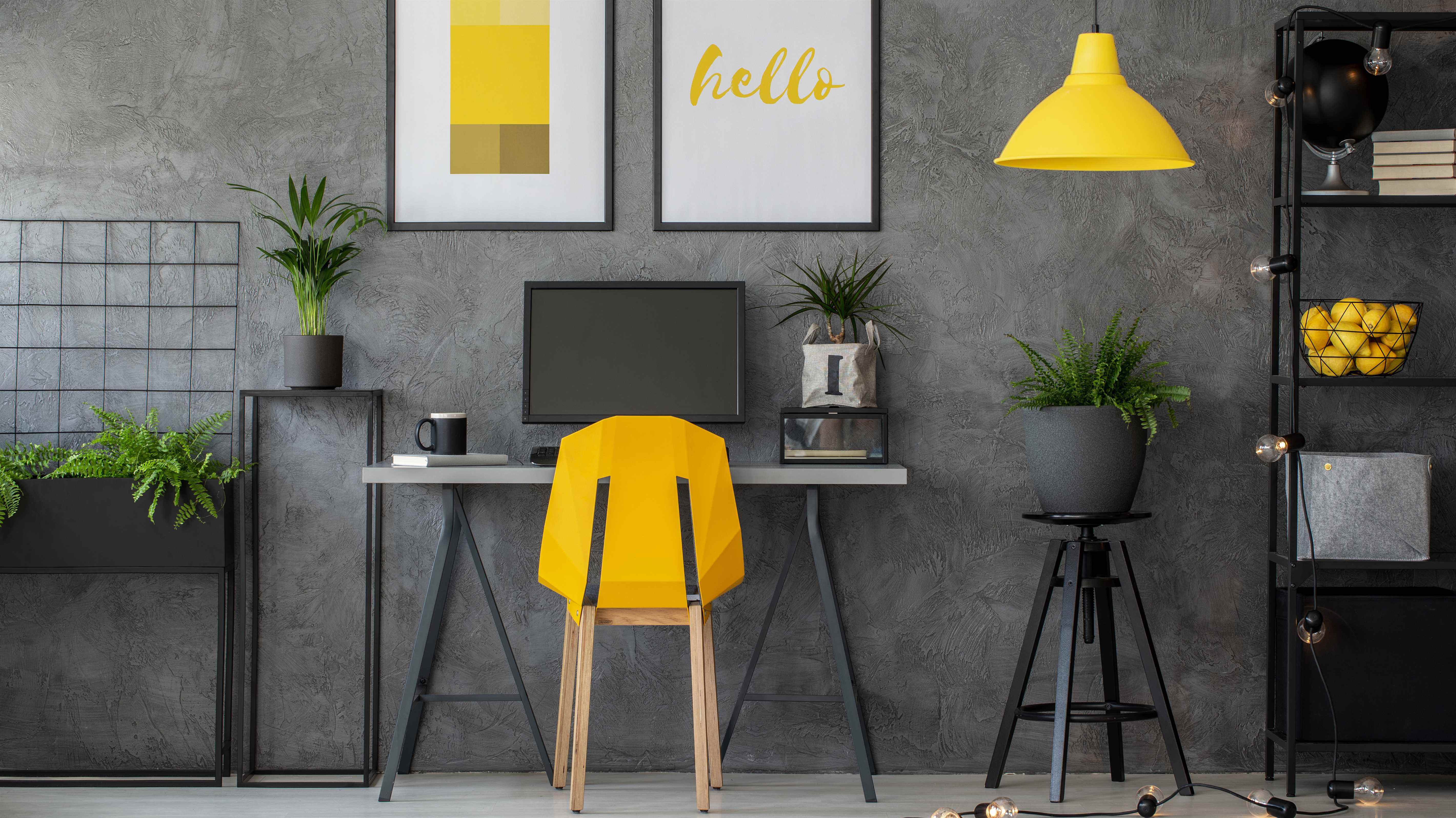 Un bureau à domicile sur le thème gris foncé avec une chaise jaune, une lampe et des citrons à décorer