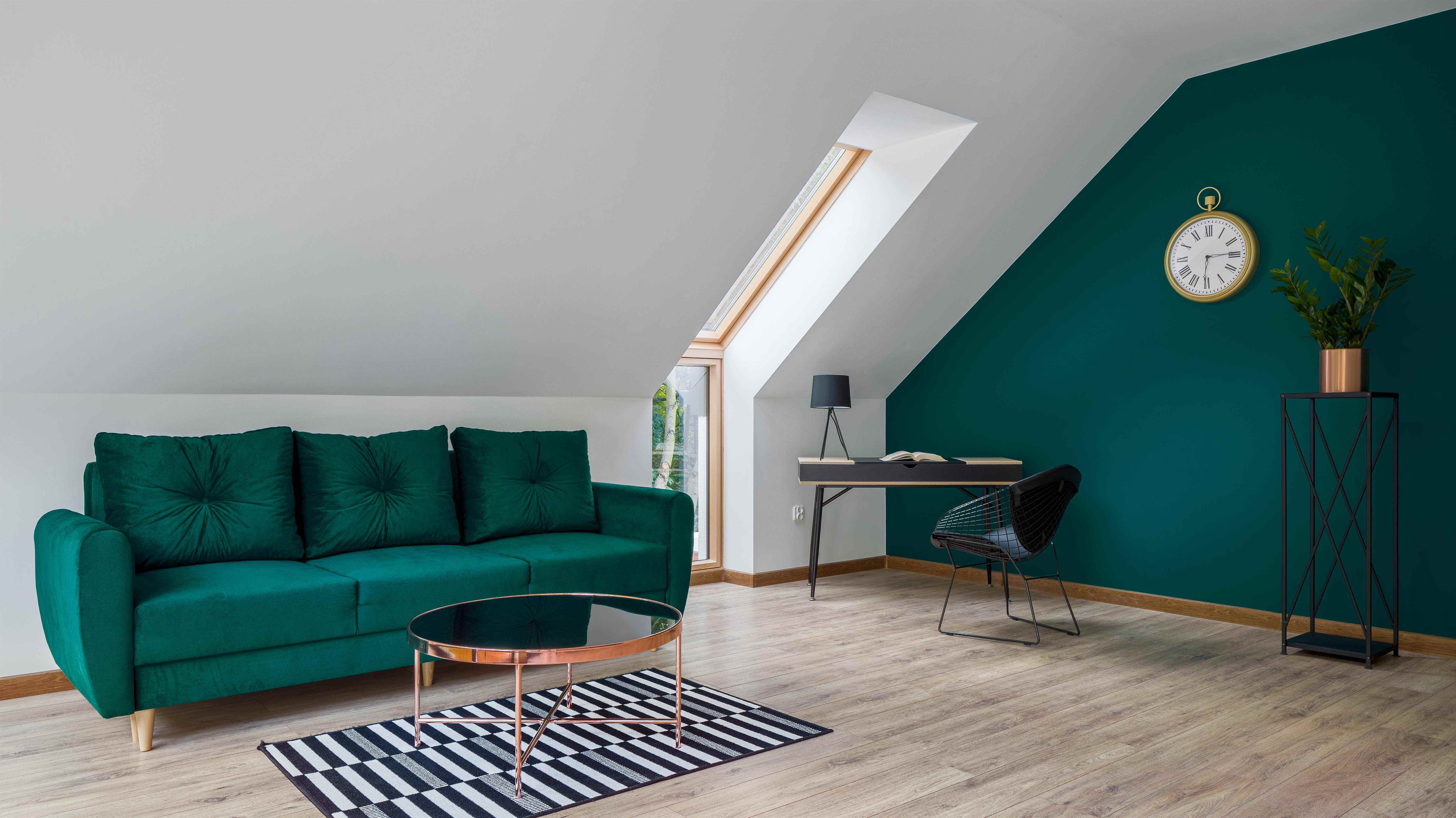 Un bureau à domicile dans le loft avec un canapé vert et un mur d'accent vert