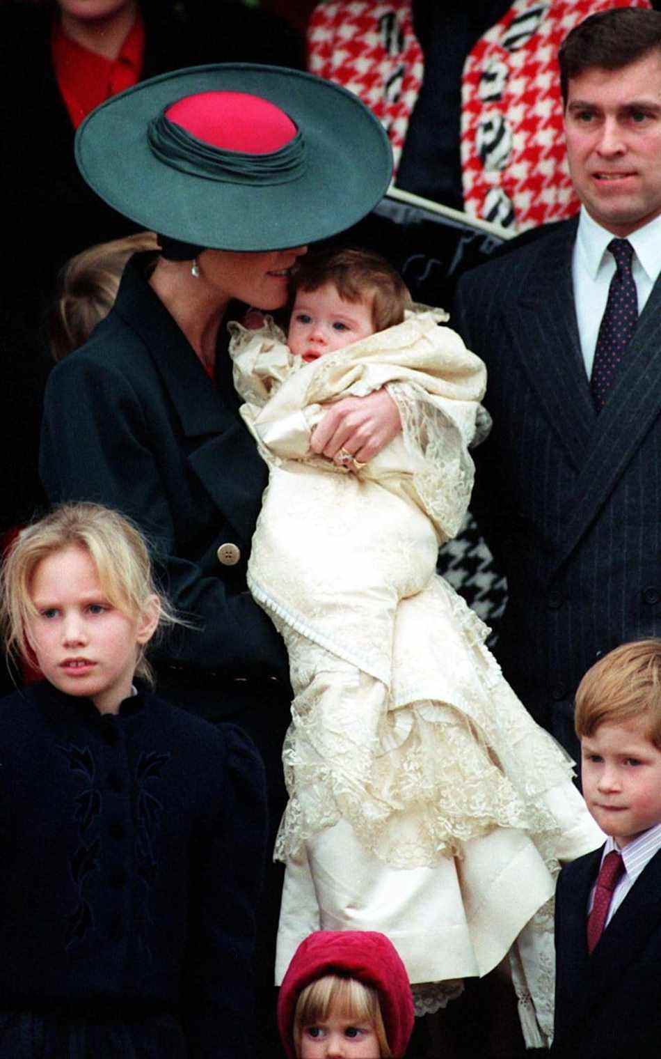 Baptême de la princesse Eugénie en 1990 : le duc d'York regarde la duchesse d'York embrasser leur bébé, la princesse Eugénie.  Sur la photo figurent également les cousins ​​​​de la princesse Eugénie, Zara Phillips (en bas à gauche) et le prince Harry - PA Archive