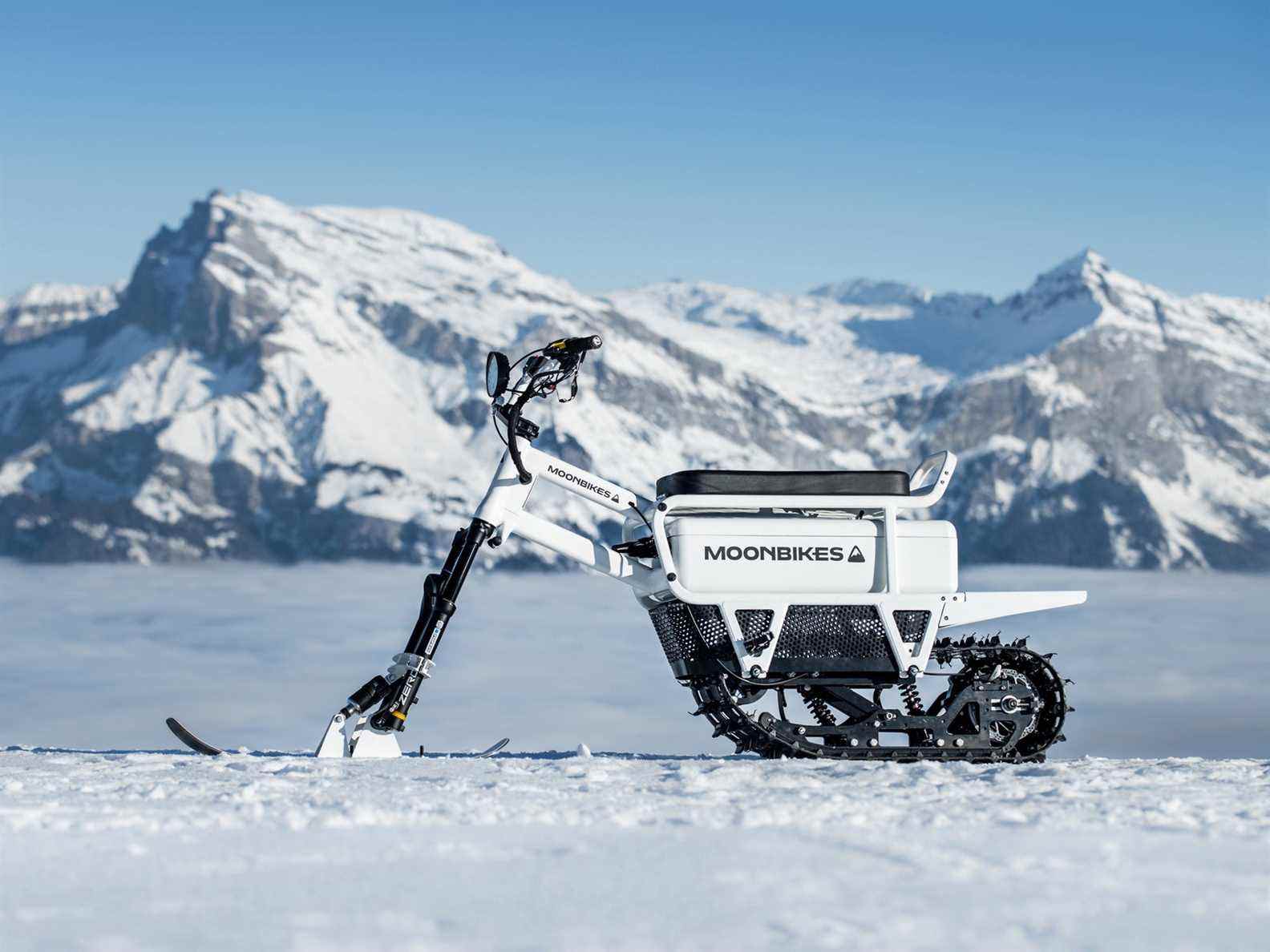 Moonbike garé dans la neige avec des montagnes enneigées en arrière-plan