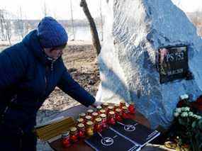 Un parent place une bougie lors d'une cérémonie commémorative de la destruction de la PS752 dans l'espace aérien iranien, à Kiev, en Ukraine.