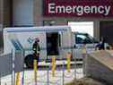 Un travailleur de la santé aide à décharger un véhicule de service de civière à l'Hôpital Saint-Boniface de Winnipeg, au Manitoba.