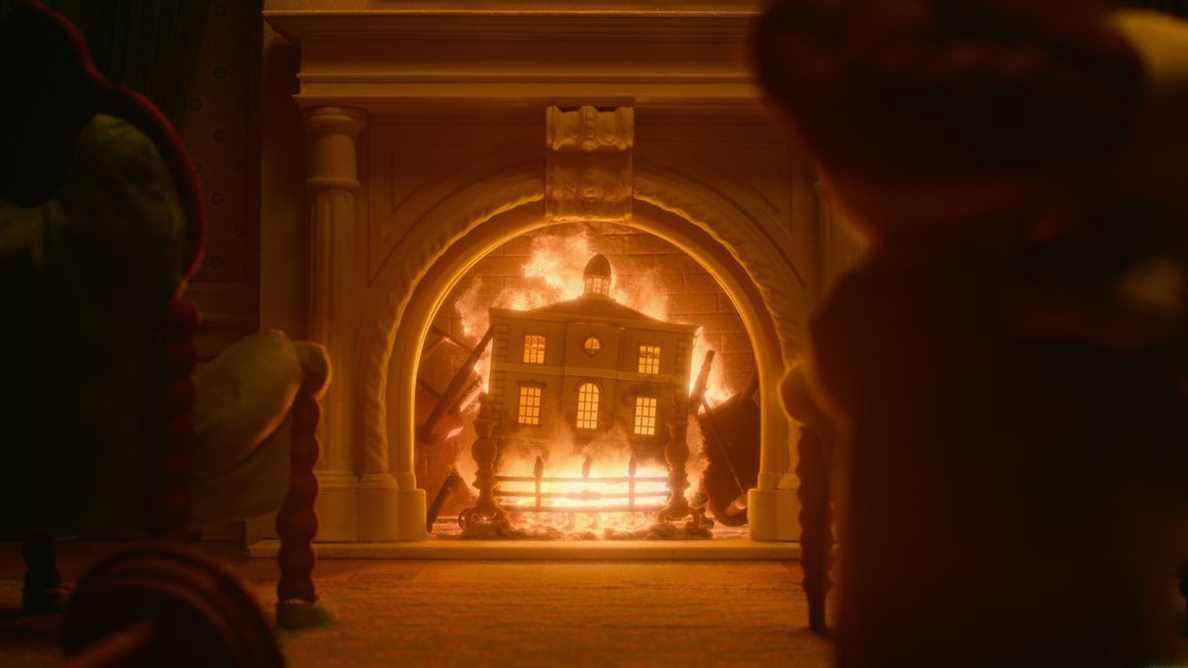 Une maison de poupée brûle dans une cheminée.