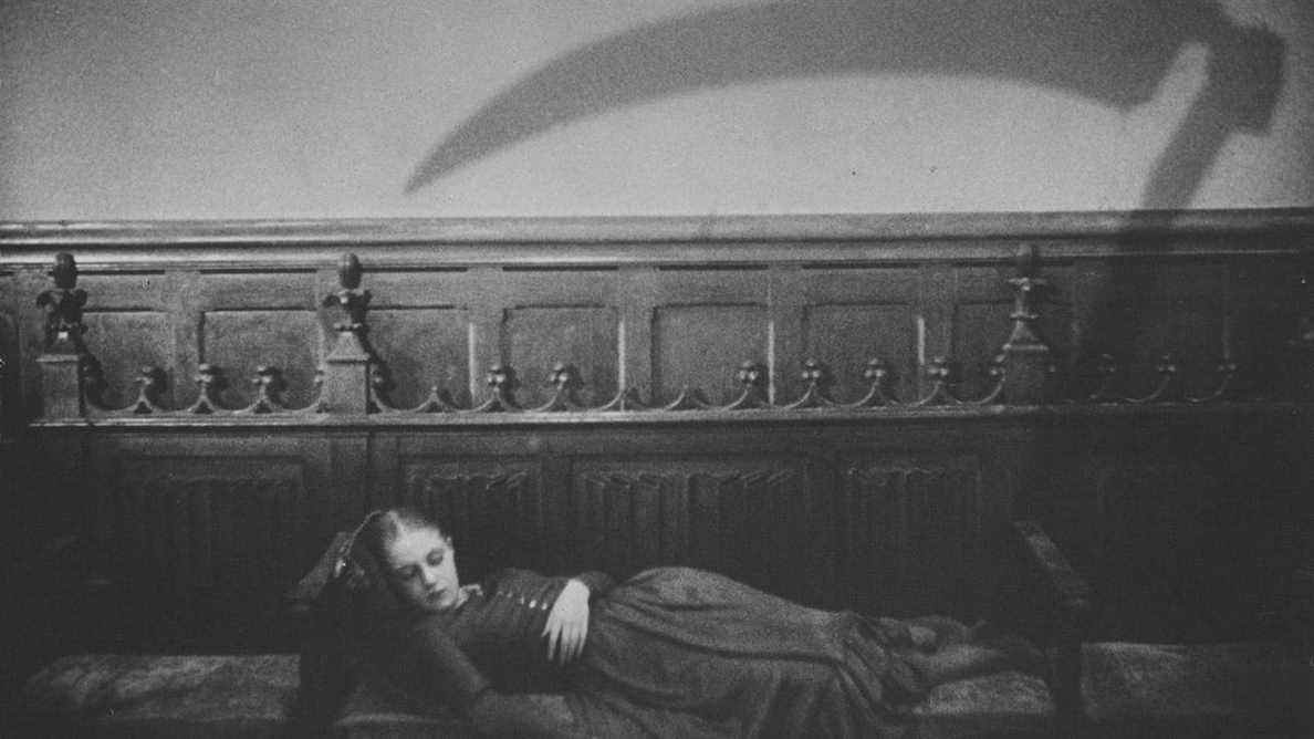 Rena Mandel inconsciente sur un canapé avec l'ombre d'une faux au-dessus de sa tête dans Vampyr (1932)