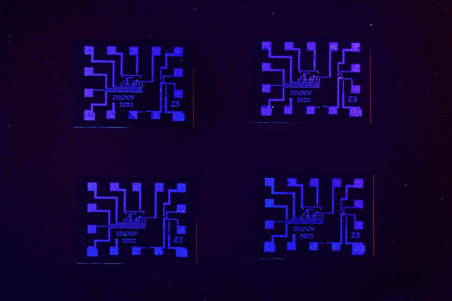 Gros plan de la troisième génération de puces Zeloof sous une lumière bleue et violette