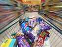 Un chariot plein de produits d'épicerie est poussé le long d'une allée dans un supermarché Morrisons à Crawley, Royaume-Uni