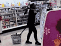 Femme tenant une pioche tout en tirant le panier en magasin.