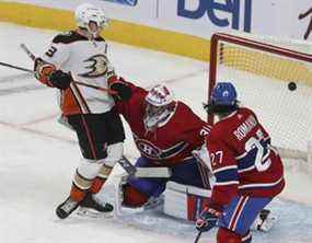 Jakob Silfverberg (33 ans) des Ducks d'Anaheim regarde la rondelle passer devant le gardien de but des Canadiens de Montréal Cayden Primeau et Alexander Romanov (27 ans) lors de l'action de première période à Montréal le jeudi 27 janvier 2022.