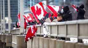 Les partisans des chauffeurs de camion agitent des drapeaux vers les voies en direction est sur l'autoroute.  401, du chemin Don Mills.  viaduc, à Toronto, Ont.  le jeudi 27 janvier 2022.