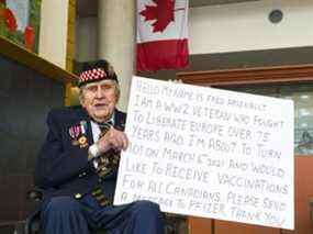 Fred Arsenault, vétéran de la Seconde Guerre mondiale, tient une pancarte demandant à Pfizer de fournir aux Canadiens suffisamment de vaccins pour son 101e anniversaire.