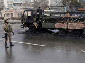 Un agent des forces de l'ordre kazakh monte la garde près d'un camion incendié tout en contrôlant des véhicules à la suite de manifestations de masse déclenchées par une augmentation du prix du carburant, à Almaty, au Kazakhstan, le samedi 8 janvier 2022.
