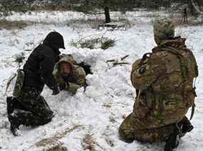 Des civils ukrainiens apprennent à construire un abri dans la neige profonde dans le cadre d'un cours accéléré sur les techniques de survie, dans une forêt à la périphérie de Kiev, le 30 janvier 2022.