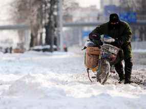 Sur cette photo d'archive, un postier avance dans une rue enneigée après de fortes chutes de neige à Pékin le 4 janvier 2010.