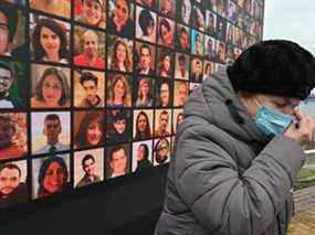 Une femme pleure devant un écran géant portant des portraits de défunts membres d'équipage et passagers du vol 752 d'Ukraine International Airlines, qui s'est écrasé en Iran un an auparavant, lors d'une cérémonie commémorative le 8 janvier 2021 sur le site d'un futur mémorial sur le Rive du fleuve Dnipro dans la capitale ukrainienne Kiev.