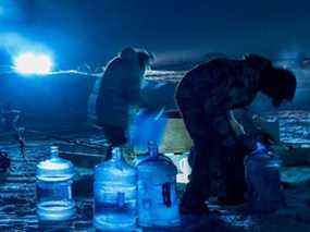 Les résidents d'Iqaluit recueillent l'eau de la rivière à travers des trous creusés dans la glace près d'Iqaluit, au Nunavut, le vendredi 14 janvier 2022.