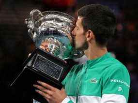 Novak Djokovic célèbre avec le trophée après avoir remporté son neuvième titre de l'Open d'Australie à Melbourne Park, Australie, le 21 février 2021.