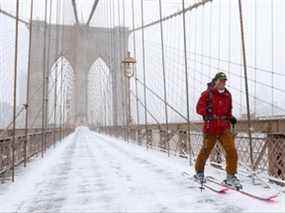 Une personne skie sur le pont de Brooklyn lors d'une tempête Nor'easter à New York, États-Unis, le 29 janvier 2022.