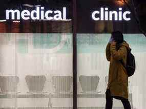 Un piéton portant un masque passe devant une clinique médicale à Toronto pendant la pandémie de COVID 19.
