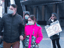 Des gens passent devant un manifestant anti-vaccin alors qu'ils se dirigent vers une clinique de vaccination contre le COVID-19 pour enfants à Toronto.