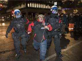 Un manifestant qui participait à une manifestation contre le couvre-feu à Montréal le 1er janvier 2022, est emmené par la police.