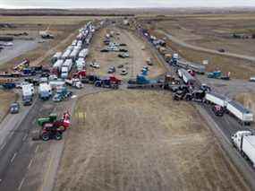 Des manifestants anti-mandat se rassemblent alors qu'un convoi de camions bloque l'autoroute du passage frontalier américain très fréquenté à Coutts, en Alberta.