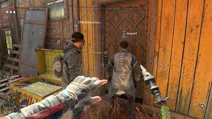 Le joueur se tient derrière deux autres humains, contrôlés par d'autres joueurs, alors qu'ils entrent dans un bâtiment en mode coopératif de Dying Light 2