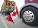 Le drapeau canadien se reflète dans un moyeu de roue alors qu'un convoi de camions bloque l'autoroute du passage frontalier achalandé des États-Unis à Coutts, en Alberta.