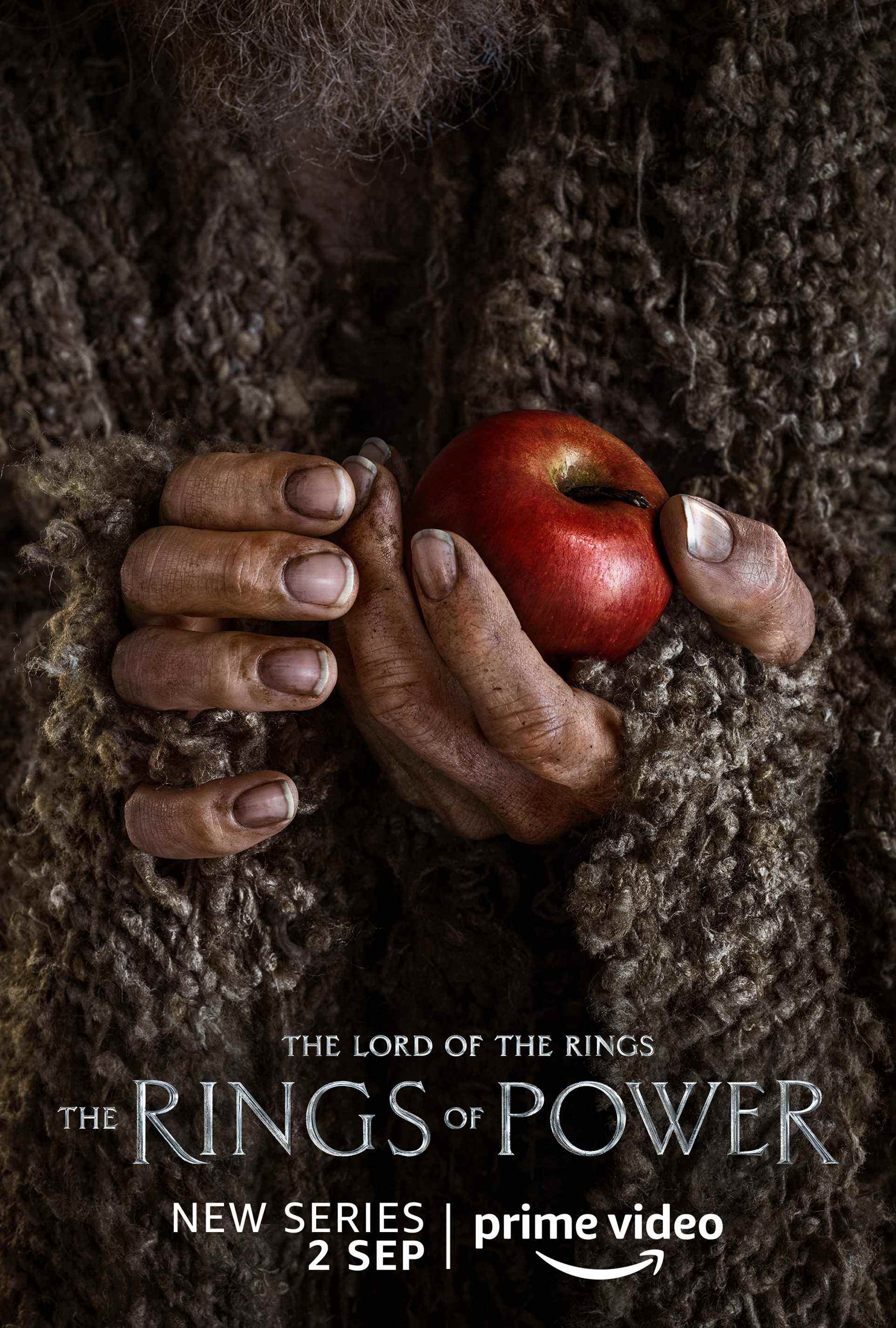 Un humain tenant une affiche de personnage de pomme pour Le Seigneur des Anneaux : Les Anneaux de Pouvoir