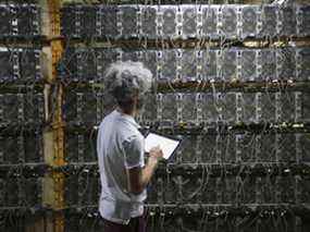 Un travailleur inspecte des machines minières Bitcoin dans une installation au Québec.